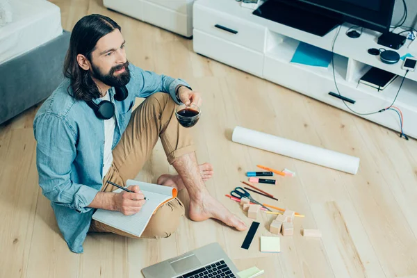 Joven Inspirado Sentado Suelo Con Una Taza Café Rodeado Artículos — Foto de Stock