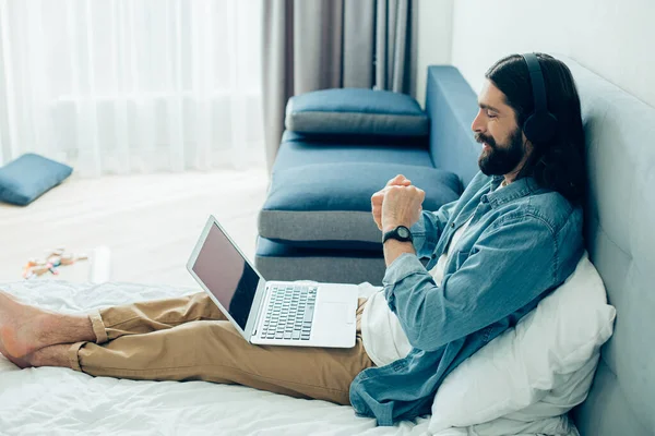 Young barefooted man watching important football match with headphones on his head