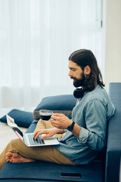 Barbudo Joven Cabello Oscuro Sentado Con Una Taza Café Sofá —  Fotos de Stock