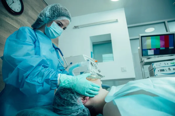 Tıbbi üniformalı doktor hastanın yanında duruyor ve yanaklarına dokunuyor.