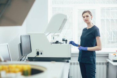 Modern ekipmanlar üzerinde kimyasal analizler yapan ve kendinden emin görünen profesyonel bir laboratuvar uzmanı.