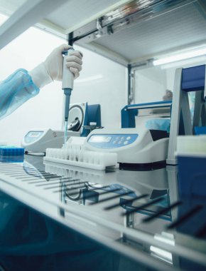 Test tüpü rafı masanın üstünde. Sıvılarla çalışırken manüel bir pipet kullanarak eldiven verin.