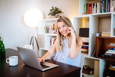 gülümseyen genç kadın p üzerinde konuşurken laptop evde çalışma