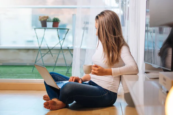 Relajado sonriendo descalza mujer sentada en el suelo mirando h — Foto de Stock