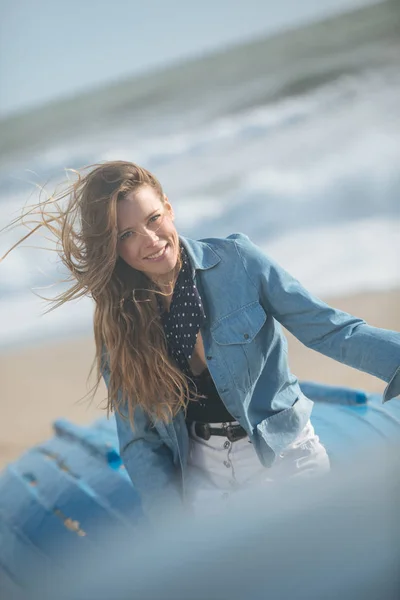 Feliz jovem sentada e posando no barco azul na frente o — Fotografia de Stock