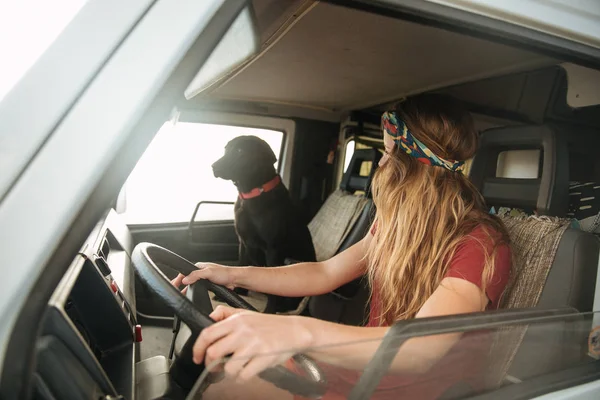 Bela jovem mulher dirigindo sua van clássica com seu cão — Fotografia de Stock