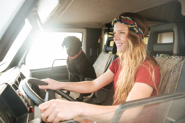 Bela jovem mulher dirigindo sua van clássica com seu cão — Fotografia de Stock