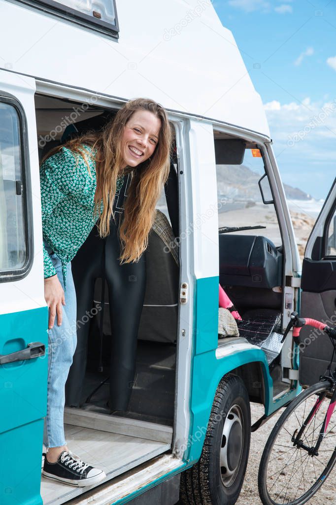 happy young woman looking at the sea from her camper van