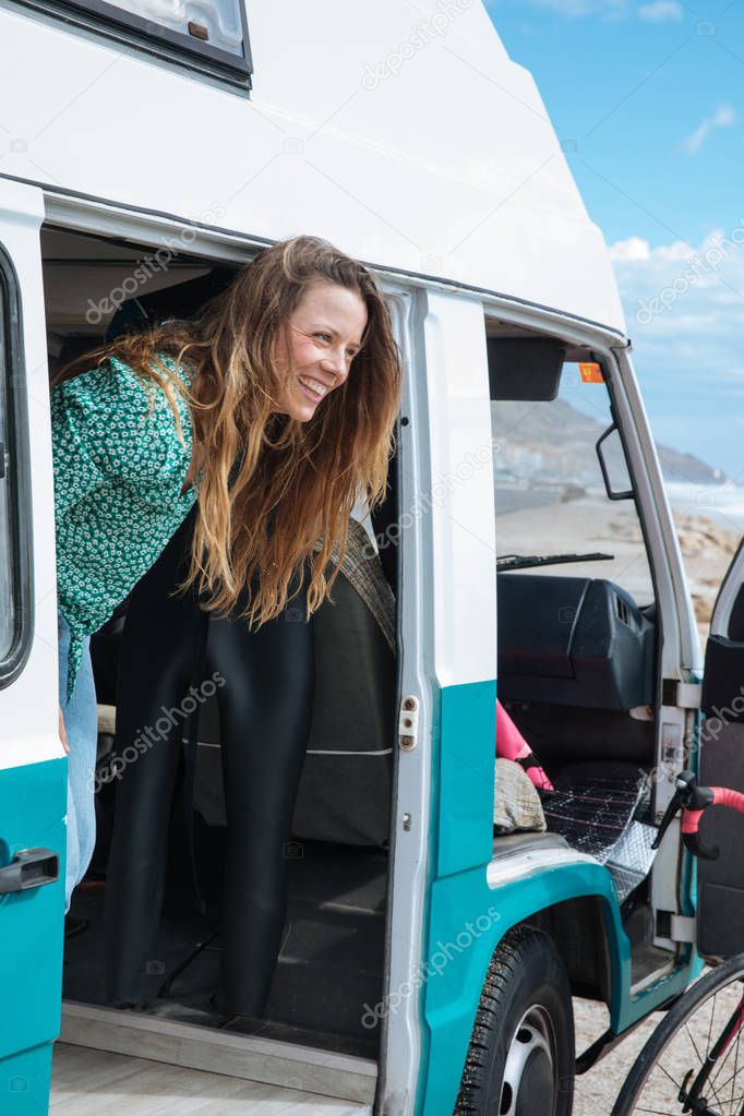 happy young woman looking at the sea from her camper van
