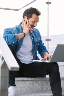 Bir merdiven ile çalışma sokakta oturan yakışıklı genç