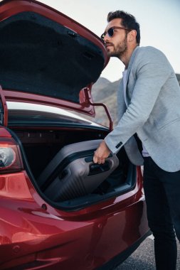 Adam seyahat bavul araba bagaja koyarak