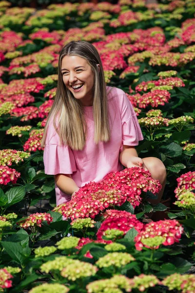 Όμορφη νεαρή γυναίκα σε ένα εξαιρετικό πεδίο από ροζ ορτανσίες (H — Φωτογραφία Αρχείου