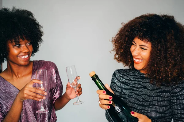 Portrait deux joyeuses femmes africaines noires américaines excitées aux cheveux bouclés célébrant une fête d'anniversaire avec du champagne sur fond blanc. S'amuser, robes de luxe, rire, bonheur . — Photo