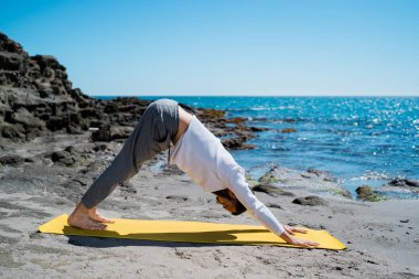 Yoga yapan genç adam doğada denize kapanıyor.