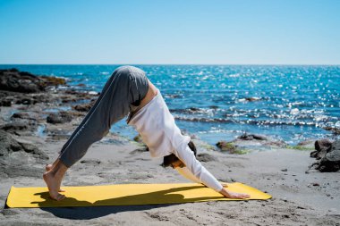 Adam sahilde meditasyon yapıyor ve pratik yapıyor.