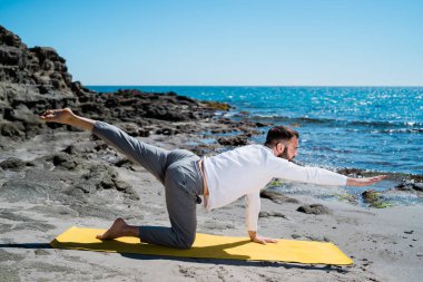 Adam sahilde meditasyon yapıyor ve pratik yapıyor.