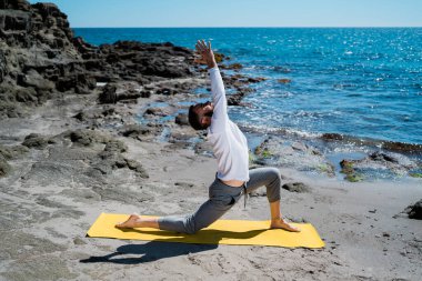 Adam sahilde meditasyon yapıyor ve pratik yapıyor.