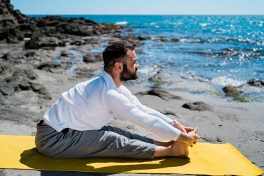 Kafkas Adam doğal bir plajda yoga yapıyor.