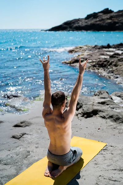 Fitter junger Mann meditiert in Yogaposition am Strand — Stockfoto