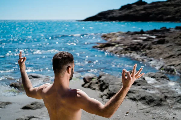 Fit jeune homme méditant dans une position de yoga sur une plage — Photo