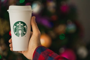 New York, Usa - 24 Kasım 2019: Man Holding a Original Tall Starbucks Cup on a Christmas Tree Background.