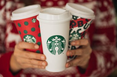 New York, Usa - 4 Aralık 2019: Üç Uzun Starbucks Kupası 'nda Noel süveteri giyen bir kadının yakın çekimi. 2019 Noel Tatili için Bir Orijinal Kupa ve İki Tasarım.