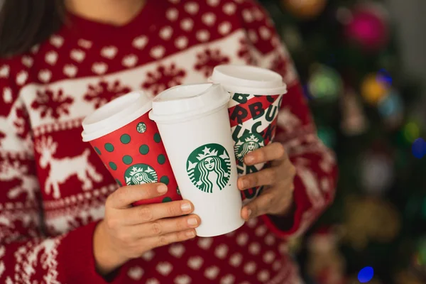 New York, Usa - 4 Aralık 2019: Üç Uzun Starbucks Kupası 'nda Noel süveteri giyen bir kadının yakın çekimi. 2019 Noel Tatili için Bir Orijinal Kupa ve İki Tasarım.