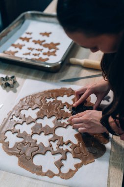 Zencefilli kurabiye yapan genç bir kadın. Noel hazırlığı, süslü zencefilli kurabiye adamlar, çiğ hamur, metal kesici. El yapımı zencefilli kurabiye.