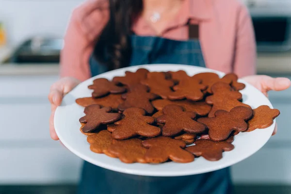 Das Bild zeigt eine Frau, die in ihrer Küche ein selbst gebackenes Lebkuchengebäck auf einem Tablett hält. hausgemachte Lebkuchen zu Weihnachten. — Stockfoto