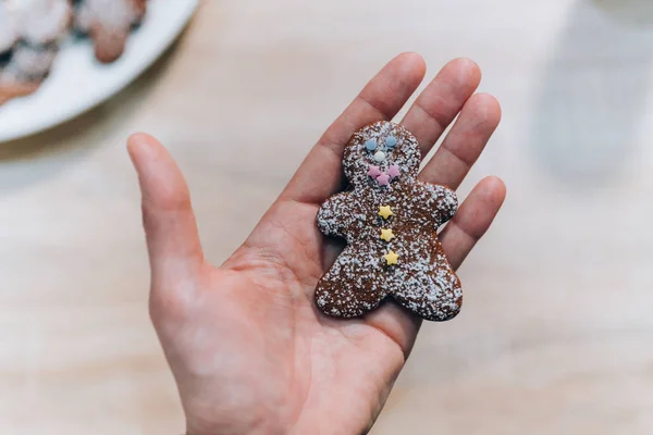 Woman hand holding colorful decorated gingerbread man cookies. Homemade Christmas cookies. — Stock Photo, Image