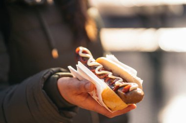 Kızarmış domuz sosisi yiyen kadın ketçaplı bratwurst, hardal, buğday ekmeğinde mayonez yiyor.
