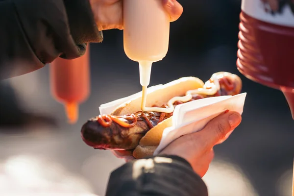 焼きポークソーセージにトマトソース、マヨネーズ、マスタードをかける女性｜Bratwurst at a Germany Market. — ストック写真