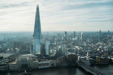 Gün batımında gökdelenle Londra 'nın havadan görünüşü ve Thames nehri. Gökyüzünde gri bulutlar var. Londra 'nın merkezindeki finans bölgesi Sky Garden' daki izleme platformundan..