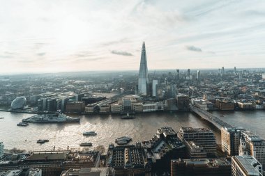 Gün batımında gökdelenle Londra 'nın havadan görünüşü ve Thames nehri. Gökyüzünde gri bulutlar var. Londra 'nın merkezindeki finans bölgesi Sky Garden' daki izleme platformundan..