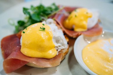 Lezzetli kahvaltı. Benedict usulü yumurta, kızarmış İngiliz keki, jambon, haşlanmış yumurta ve leziz Hollandaise sosu..