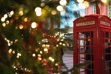 Londra 'da Noel zamanı: Londra' nın merkezinde gece vakti aydınlatılmış bir Noel Ağacı önünde kırmızı bir telefon kulübesi.