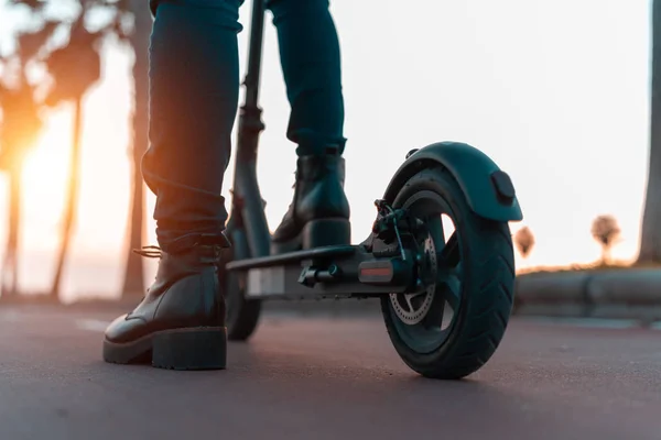 Imagen de cerca de una joven en un scooter eléctrico durante el atardecer — Foto de Stock