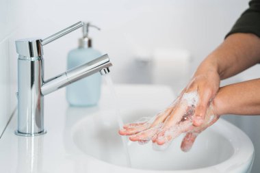 Hijyen. Temizlikçi Eller. Ellerimi sabunla yıkıyorum. Banyoda ellerini sabunla yıkayan genç bir kadın, yakın plan. Covid 19. Coronavirüs.