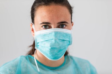 Koronavirüse karşı koruyucu maske takan genç bir kadın doktor. Tıbbi kişisel koruma ekipmanları.