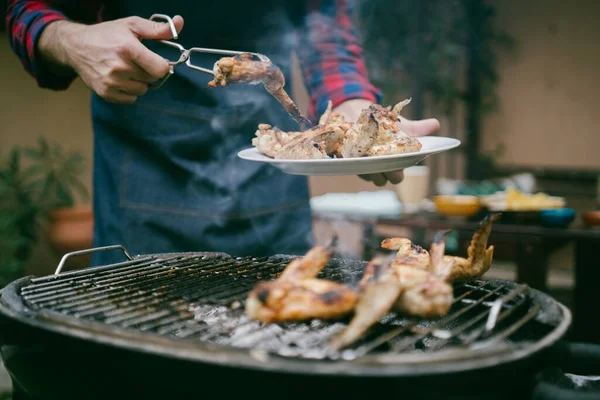 家の庭で美しい夏の日に屋外ランチのためのバーベキューグリルでおいしい翼を調理する男 — ストック写真