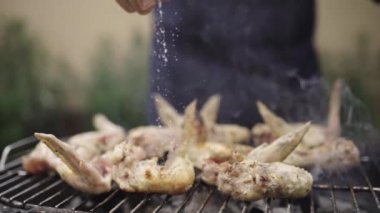 Barbekü ızgarasında lezzetli kanatlar pişiren adam dışarıda öğle yemeği için güzel bir yaz günü bir ev bahçesinde