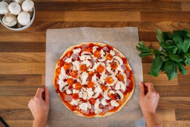 Ev yapımı İtalyan pizzalı margherita hazırlayan bir kadının en iyi görüntüsü. Tahta atölyede klasik İtalyan pizza hazırlığı.