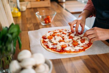 Bir kadının elleri geleneksel margarita pizzasına vişneli domates ekliyor. Orijinal İtalyan pizzasının hazırlığı