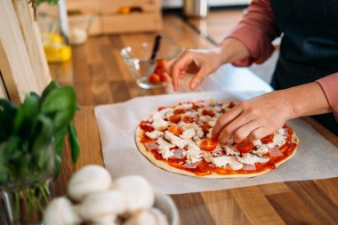 Bir kadının elleri geleneksel margarita pizzasına vişneli domates ekliyor. Orijinal İtalyan pizzasının hazırlığı
