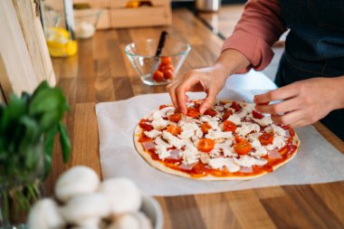 Bir kadının elleri geleneksel margarita pizzasına vişneli domates ekliyor. Orijinal İtalyan pizzasının hazırlığı