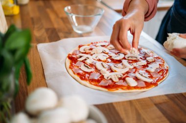 Geleneksel margarita pizzasına mantar ekleyen kadın elleri. Orijinal İtalyan pizzasının hazırlığı