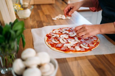 Geleneksel margarita pizzasına mantar ekleyen kadın elleri. Orijinal İtalyan pizzasının hazırlığı