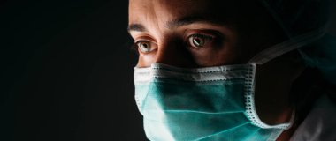 Kadın doktor koruyucu yüz maskesi takıyor ve siyah arka planda koronavirüse karşı. Panorama panorama tıbbi personel önleyici ekipman. Doktor Coronavirus 'u izole et..