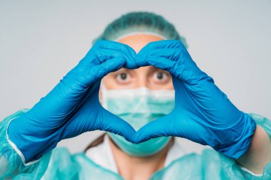 COVID-19 Coronavirus salgını mutlu kadın doktor tıbbi maske ve lateks eldivendeki eller kalbin sembolünü gösteriyor. Kalp için doktor. Tıp uzmanlarımızı seviyoruz..