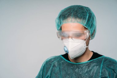Puslu gözlükleri, tıbbi maskesi, lateks eldivenleri ve beyaz arka planda kopya alanı olan virüs korumalı giysileri olan genç bir doktor. COVID-19 Koronavirüs salgını.